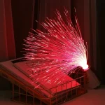 Pétala de fibra ótica vermelha brilhante, criando um efeito de fogo de artifício, colocada numa prateleira com livros, ambiente acolhedor e moderno.