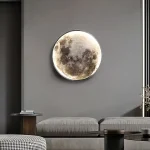 Decoração de parede representando a lua em relevo, iluminada, em um interior moderno com sofá cinza e mesa de centro.
