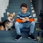 Menino jovem com um cachorro brincando com um Cubo de Rubik em uma escada, ambiente descontraído e lúdico.