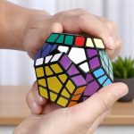 Um cubo de puzzle colorido, usado para estimulação mental e entretenimento, apresentado num ambiente interior com uma planta ao fundo.
