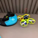Mini drone com quatro hélices coloridas e capacete de proteção, ideal para aprender a pilotar com segurança. Perfeito para entusiastas de tecnologia e gadgets.