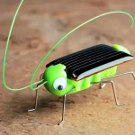Chip solar em forma de inseto com corpo em metal, asas em plástico preto e olhos em plástico branco com pupilas pretas.