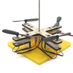 Drone educativo com hélices, estrutura em madeira e base em espuma amarela, concebido para o aprendizado de robótica e mecânica. Perfeito para projetos científicos e educativos.