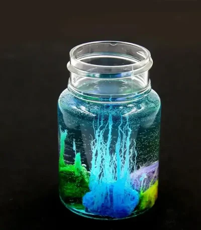 Vaso de vidro contendo uma experiência científica com líquidos coloridos e bolhas, ilustrando um fenômeno químico ou físico cativante.