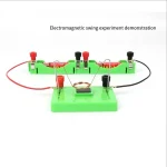 Dispositivo educativo ilustrando uma experiência de oscilação eletromagnética com bobinas, ímãs e fios conectados em uma base verde.