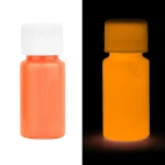 Frasco de tinta fluorescente laranja visível em luz normal e luminescente no escuro, perfeito para decoração ou projetos artísticos luminosos.