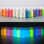 Potes de tinta fosforescente de diferentes cores, visíveis à luz normal e que brilham no escuro, perfeitos para decoração e projetos artísticos luminosos.