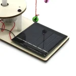 Painel solar ilustrando uma experiência educativa com um objeto científico, incluindo um dispositivo solar, um fio vermelho e uma bola suspensa, perfeito para o aprendizado de energia solar.