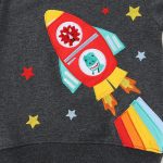 Vêtement pour enfant avec motif de fusée en patchwork coloré, étoiles et flammes, idéal pour une décoration ludique et scientifique.
