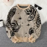 Camisola de lã bege com padrões de galáxias e estrelas pretas, perfeita para um look aconchegante e original.
