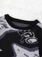 Imagem de um suéter com design astronômico, com motivos de galáxias e estrelas em tons de preto, cinza e branco, sobre um fundo de felpa branca.