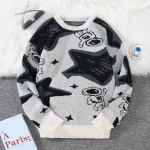 Camisola de lã cinza, preta e branca com padrões de personagens de desenhos animados e estrelas, perfeita para um look casual e moderno.