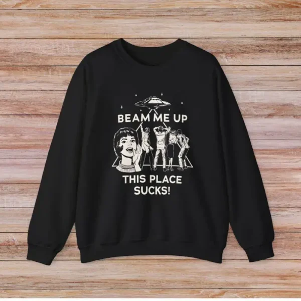 T-shirt preta com ilustração humorística e texto "Beam me up, this place sucks!" para os amantes de ciência e humor.