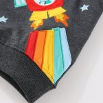 Roupa infantil com patch científico colorido, estampa de foguete e estrelas, em tecido cinza escuro, ideal para uma decoração lúdica e educativa.