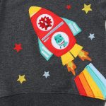 Roupa infantil com estampa de foguete em patchwork colorido, estrelas e chamas, ideal para uma decoração lúdica e científica.