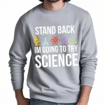 Camisola cinza com mensagem humorística sobre ciência, "Afastem-se, vou tentar ciência", com ícones de laboratório coloridos.