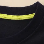 T-shirt preta com faixa refletora amarela, ideal para segurança e desporto, fabricada em algodão de alta qualidade para um conforto ideal.