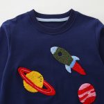 Camisola infantil bordada com padrão de foguete e planetas.