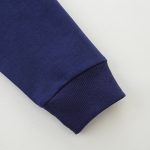 Manga de blusão em algodão azul-marinho com punhos canelados, vista aproximada.