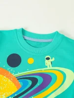 T-shirt infantil com design de astronauta e planetas coloridos, ideal para os amantes do espaço e da ciência, perfeita para uma decoração lúdica e educativa.