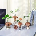 Vasos de vidro em forma de cogumelos com plantas verdes e flores, decoração de escritório moderna e original.