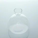 Frasco de vidro transparente usado em laboratório científico, com um gargalo estreito e uma forma arredondada, ideal para experiências e decoração.