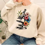 Sweatshirt com padrão de microscópio rodeado de flores coloridas, perfeito para os amantes de ciência e decoração original.