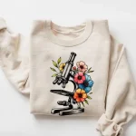 Placa com microscópio e flores coloridas, ideal para decoração científica ou para os amantes de biologia.