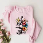 Confira esta ilustração de microscópio rodeado de flores coloridas, perfeita para uma t-shirt original e científica.