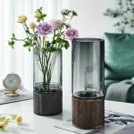 Vaso de vidro transparente com base de madeira, ideal para decoração interior e apresentação de flores frescas ou artificiais.