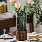 Flores rosas em um vaso de vidro com base de madeira, decoração elegante e moderna para interiores.