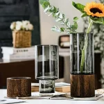 Vaso de vidro com base de madeira, ideal para flores frescas ou artificiais, trazendo um toque natural e elegante à sua decoração.